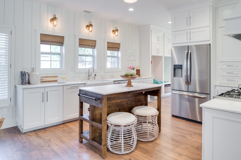 Kitchen - coastal u-shaped medium tone wood floor and brown floor kitchen idea in DC Metro with a farmhouse sink, shaker cabinets, white cabinets, stainless steel appliances, an island, quartzite countertops, white backsplash and wood backsplash