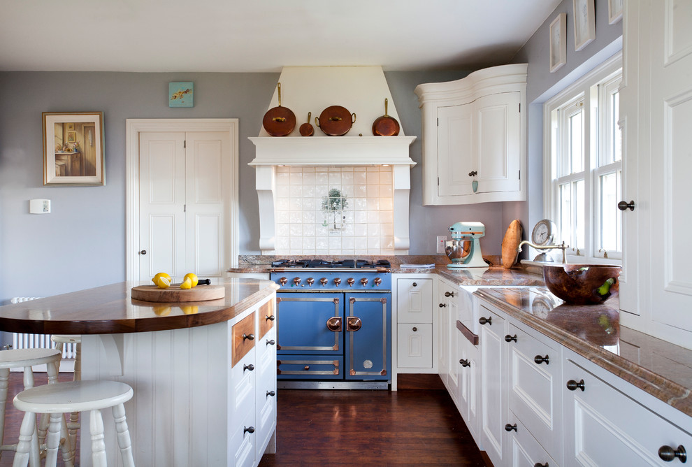 Foto på ett vintage l-kök, med en rustik diskho, luckor med infälld panel, vita skåp, grått stänkskydd, färgglada vitvaror, mörkt trägolv och en köksö