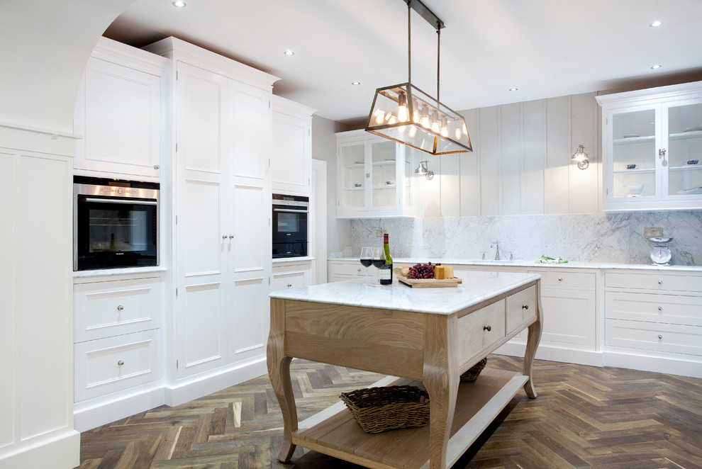Photo of a large bohemian u-shaped kitchen pantry in Dublin with a submerged sink, beaded cabinets, white cabinets, marble worktops, white splashback, stone slab splashback, stainless steel appliances, dark hardwood flooring and an island.