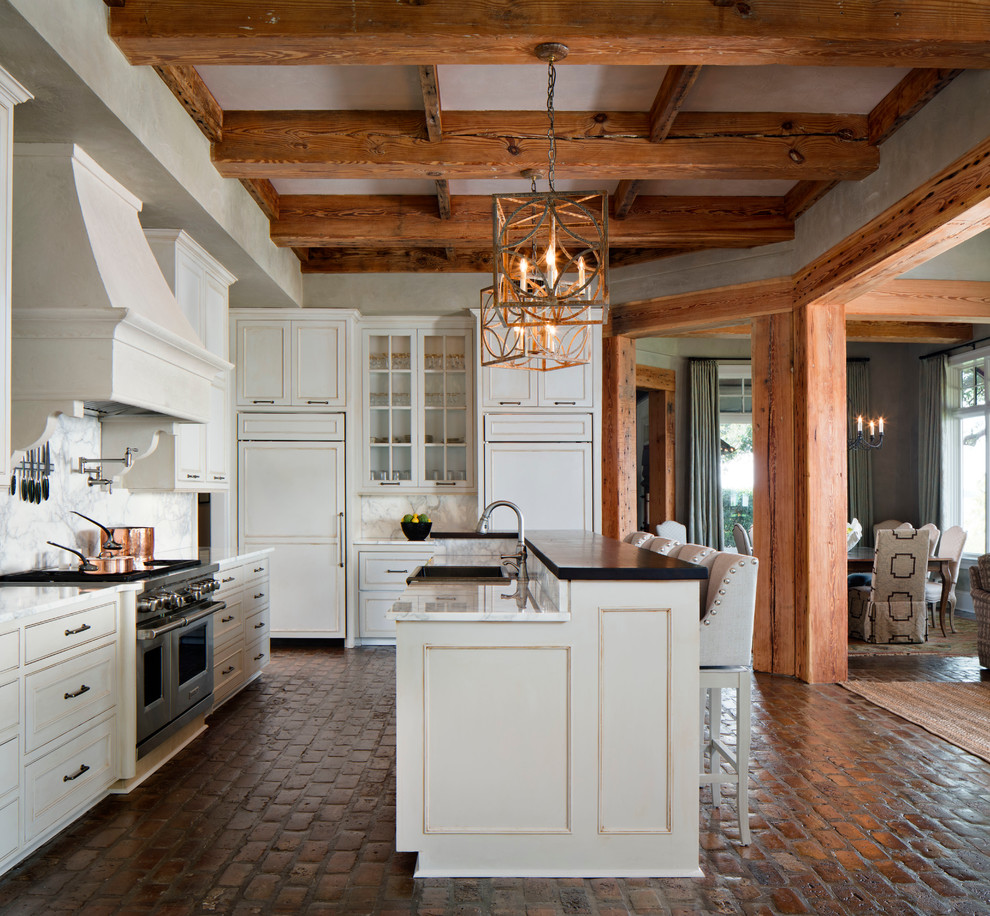 Inspiration för stora klassiska kök, med luckor med profilerade fronter, vita skåp, marmorbänkskiva, vitt stänkskydd, integrerade vitvaror, tegelgolv, en rustik diskho, stänkskydd i sten och en köksö