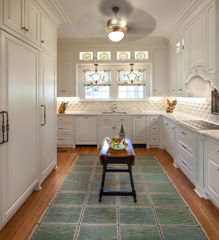 Diseño de cocina tradicional con puertas de armario blancas, encimera de cuarcita, suelo de madera en tonos medios y salpicadero blanco