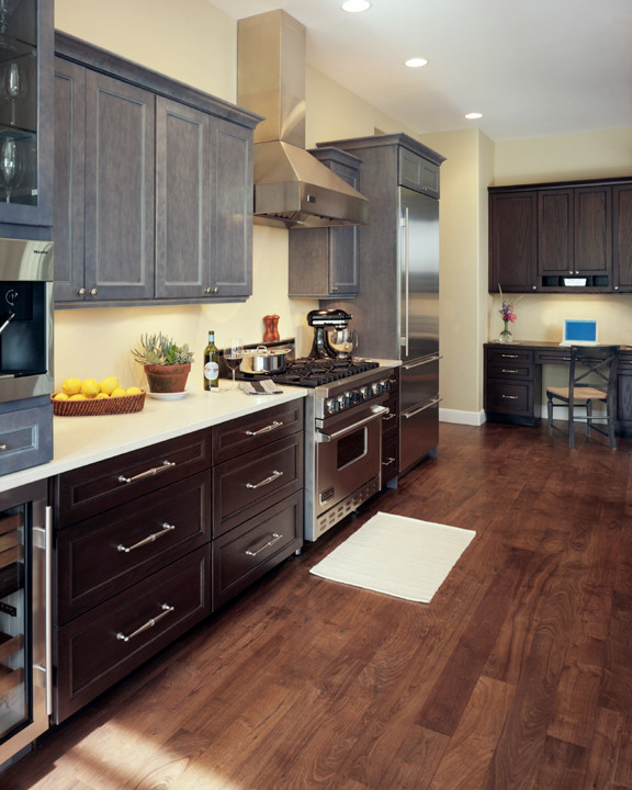 Cette photo montre une cuisine chic avec un placard avec porte à panneau encastré, des portes de placard grises et un sol en bois brun.