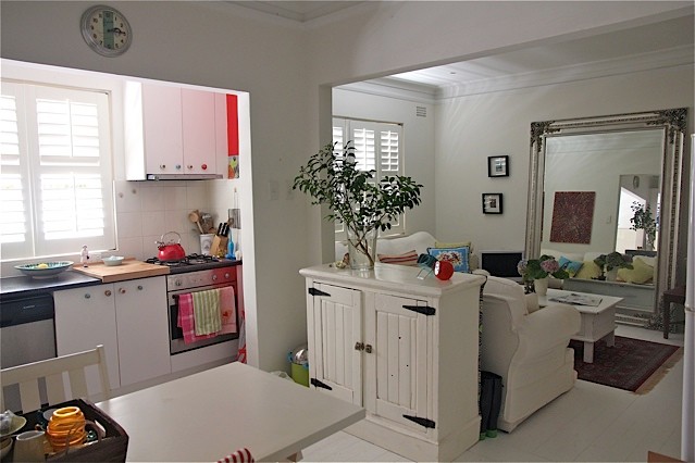 На фото: кухня в стиле фьюжн с белыми фасадами и деревянным полом с