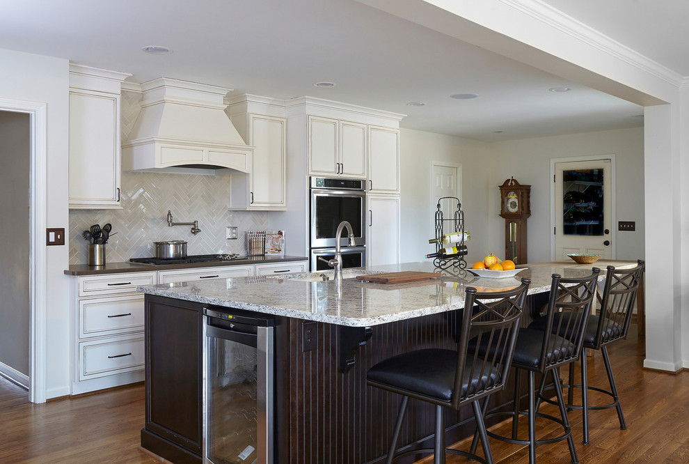 Cette photo montre une cuisine américaine tendance en L avec une crédence blanche, un électroménager en acier inoxydable, un sol en bois brun et îlot.