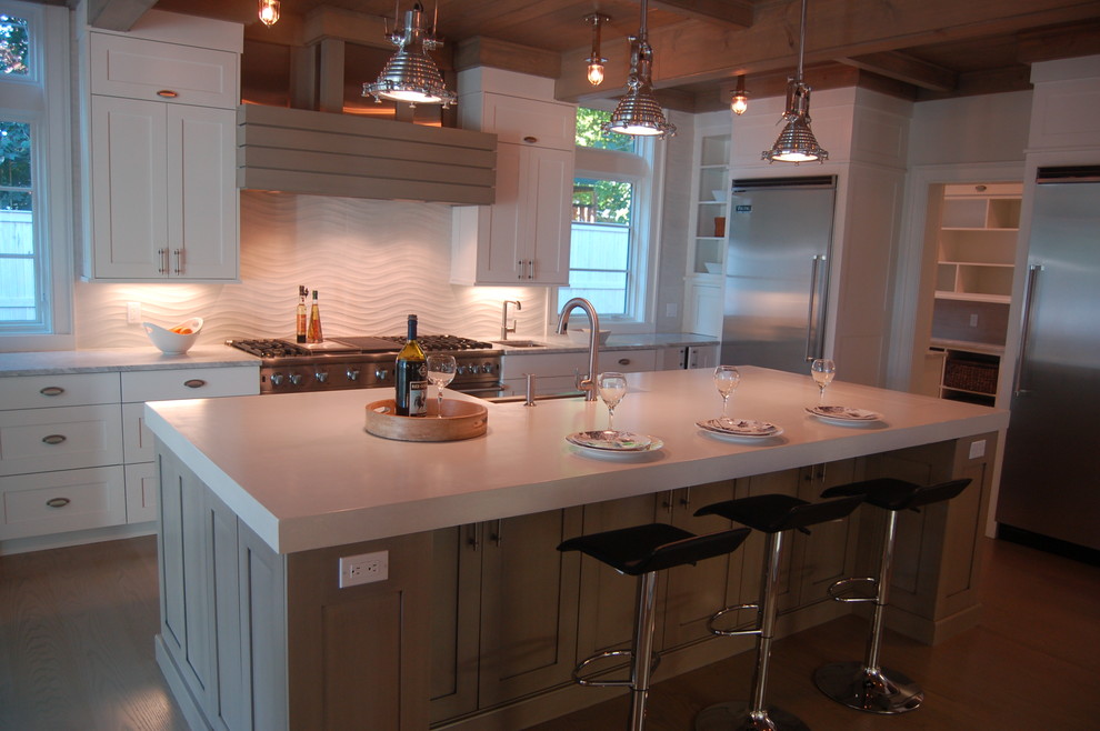 Open concept kitchen - large coastal u-shaped light wood floor open concept kitchen idea in New York with a farmhouse sink, recessed-panel cabinets, white cabinets, concrete countertops, white backsplash, ceramic backsplash, stainless steel appliances and an island