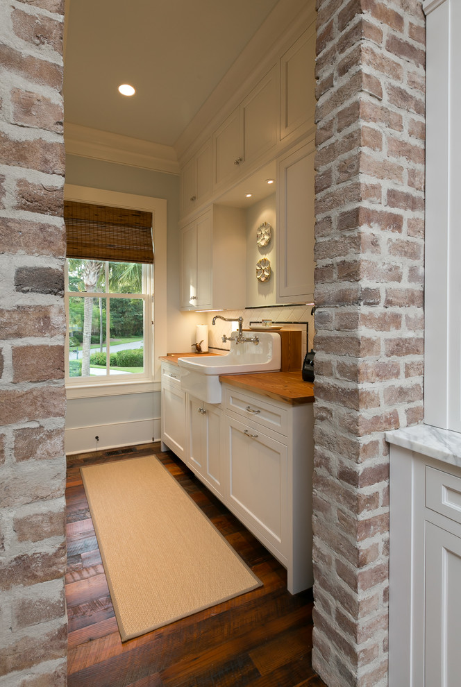 Elegant medium tone wood floor enclosed kitchen photo in Charleston with a farmhouse sink, shaker cabinets, white cabinets, wood countertops, white backsplash and ceramic backsplash