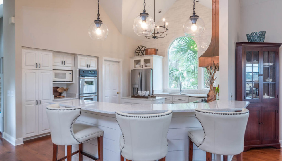Example of a mid-sized beach style u-shaped dark wood floor and brown floor open concept kitchen design in Atlanta with a double-bowl sink, raised-panel cabinets, white cabinets, quartzite countertops, white backsplash, subway tile backsplash, stainless steel appliances, an island and gray countertops