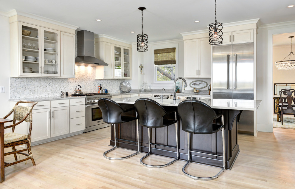 Enclosed kitchen - mid-sized traditional l-shaped light wood floor enclosed kitchen idea in Charleston with a farmhouse sink, shaker cabinets, white cabinets, marble countertops, white backsplash, mosaic tile backsplash, stainless steel appliances and an island