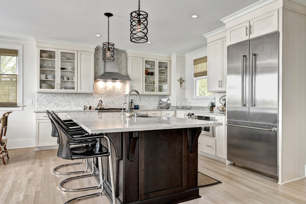 Mid-sized elegant l-shaped light wood floor enclosed kitchen photo in Charleston with a farmhouse sink, shaker cabinets, white cabinets, marble countertops, white backsplash, mosaic tile backsplash, stainless steel appliances and an island