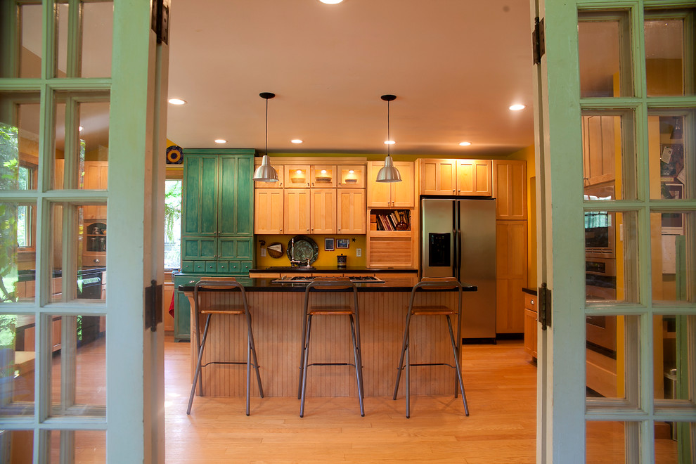 Cette photo montre une cuisine éclectique en bois brun avec un placard avec porte à panneau encastré et un électroménager en acier inoxydable.