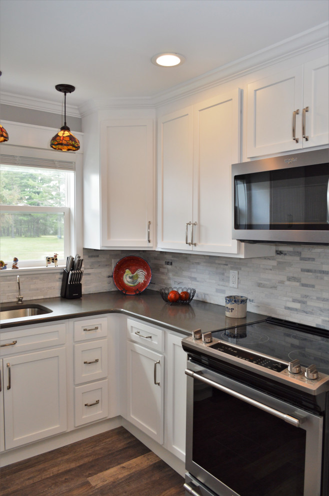 Exempel på ett mellanstort klassiskt grå grått kök, med en undermonterad diskho, skåp i shakerstil, vita skåp, bänkskiva i kvartsit, grått stänkskydd, stänkskydd i stenkakel, rostfria vitvaror, laminatgolv och brunt golv
