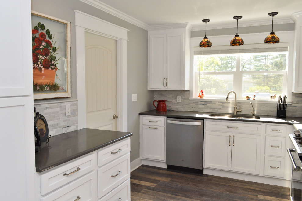 Example of a mid-sized transitional l-shaped laminate floor and brown floor eat-in kitchen design in Chicago with an undermount sink, shaker cabinets, white cabinets, quartzite countertops, gray backsplash, stone tile backsplash, stainless steel appliances, no island and gray countertops