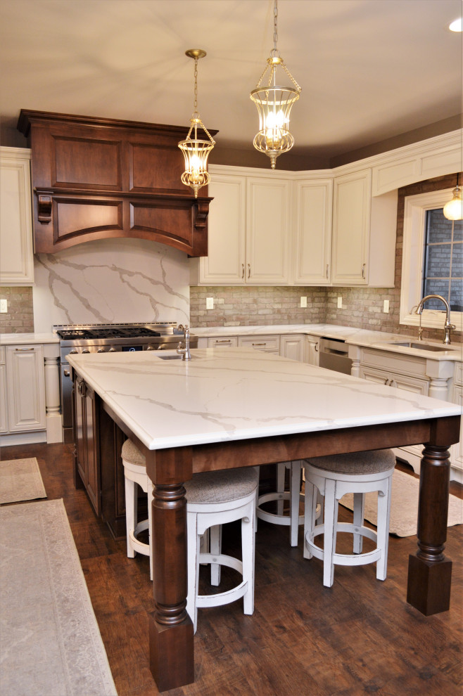 Idéer för att renovera ett mycket stort vintage vit vitt kök, med en undermonterad diskho, luckor med upphöjd panel, vita skåp, bänkskiva i kvartsit, grått stänkskydd, stänkskydd i tegel, rostfria vitvaror, mellanmörkt trägolv, en köksö och brunt golv