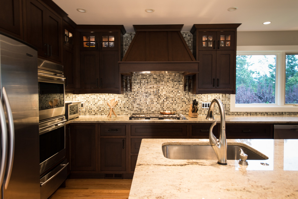Diseño de cocina de estilo americano con fregadero bajoencimera, puertas de armario de madera oscura, encimera de granito y electrodomésticos de acero inoxidable