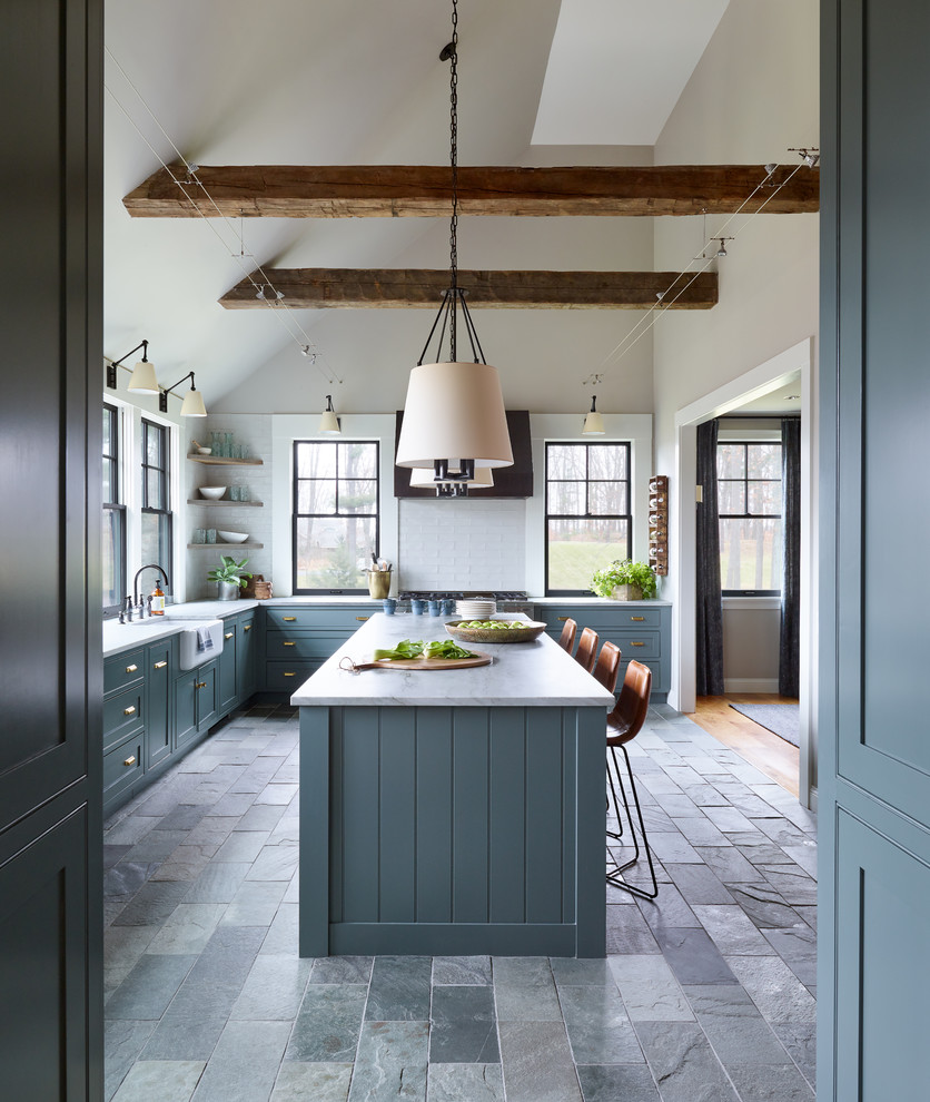 Mid-sized transitional l-shaped slate floor and gray floor enclosed kitchen photo in Boston with a farmhouse sink, shaker cabinets, blue cabinets, quartzite countertops, white backsplash, subway tile backsplash, stainless steel appliances, an island and white countertops