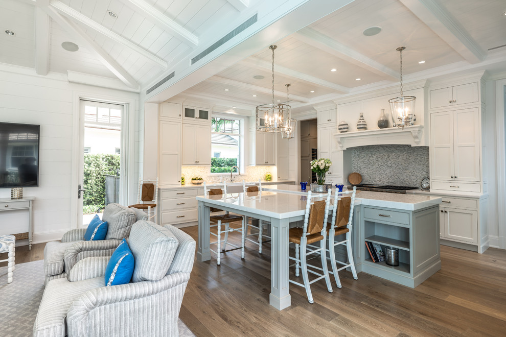 Inspiration for a medium sized beach style open plan kitchen in Other with beaded cabinets, white cabinets, marble worktops, integrated appliances, light hardwood flooring, an island, brown floors and white worktops.