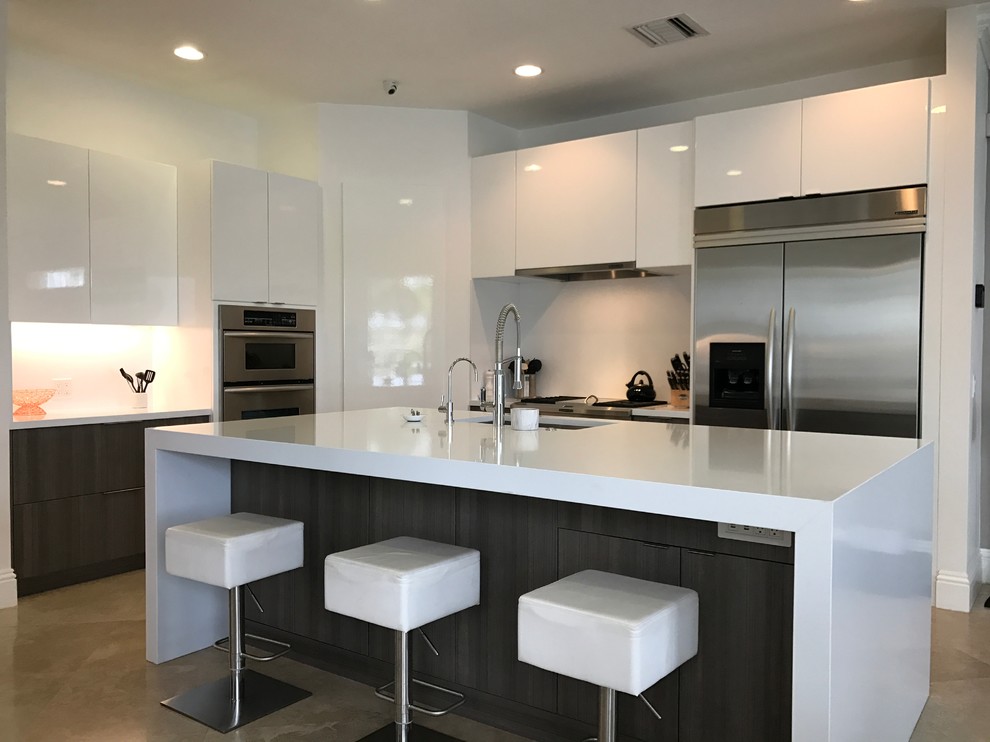Foto på ett mellanstort funkis kök, med en undermonterad diskho, släta luckor, vita skåp, bänkskiva i kvartsit, vitt stänkskydd, rostfria vitvaror och en köksö
