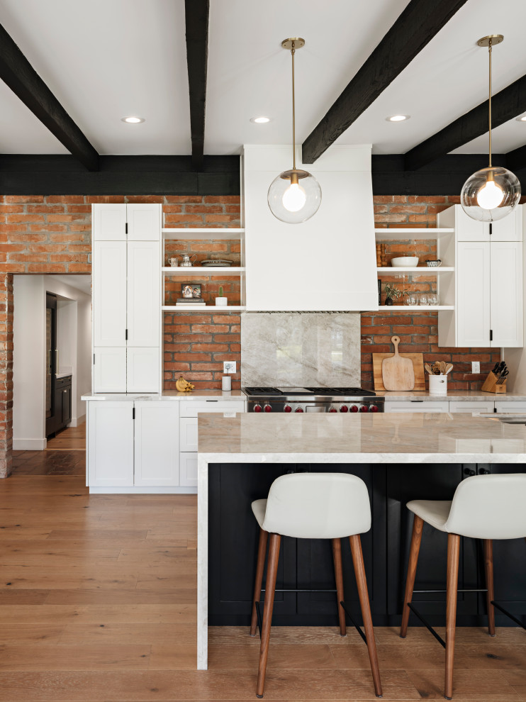Idéer för att renovera ett amerikanskt grå grått kök med öppen planlösning, med skåp i shakerstil, vita skåp, granitbänkskiva, integrerade vitvaror, mellanmörkt trägolv, en köksö, en undermonterad diskho, rött stänkskydd, stänkskydd i tegel och brunt golv