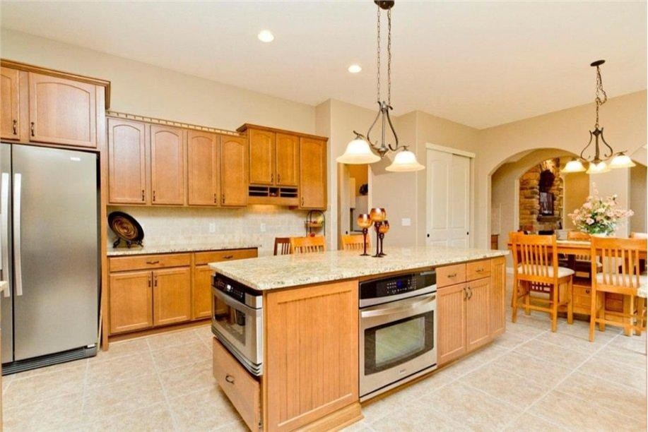 Inspiration for a large timeless u-shaped light wood floor eat-in kitchen remodel in Columbus with a double-bowl sink, recessed-panel cabinets, light wood cabinets, granite countertops, beige backsplash, ceramic backsplash, stainless steel appliances and an island
