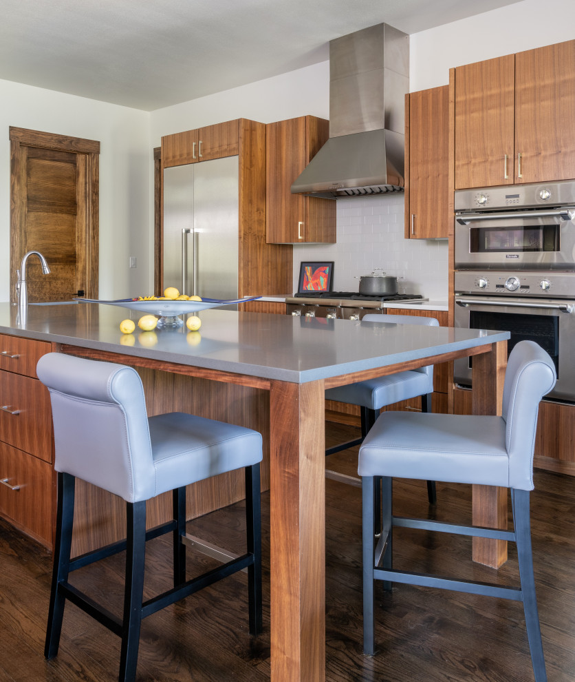 Foto di una cucina design con ante lisce, ante in legno scuro, paraspruzzi bianco, elettrodomestici in acciaio inossidabile, parquet scuro, pavimento marrone e top grigio