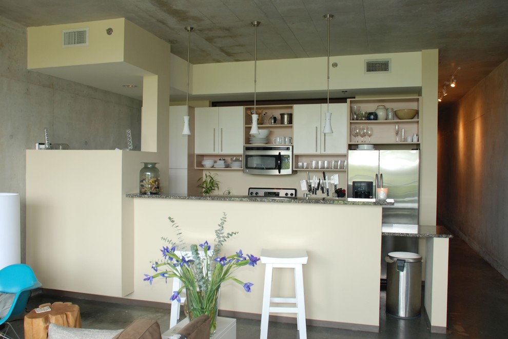 Exemple d'une cuisine parallèle moderne avec un électroménager en acier inoxydable, un placard sans porte et des portes de placard blanches.