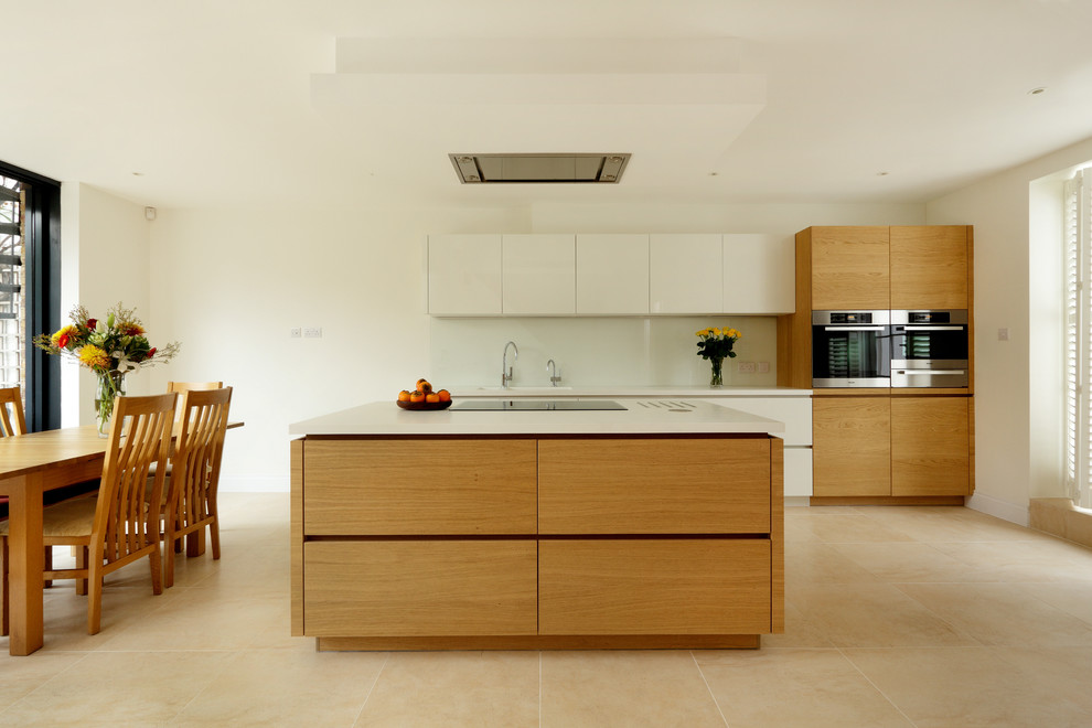 Foto på ett mellanstort funkis linjärt kök med öppen planlösning, med en integrerad diskho, släta luckor, skåp i mellenmörkt trä, bänkskiva i koppar, vitt stänkskydd, glaspanel som stänkskydd, rostfria vitvaror, klinkergolv i porslin och en köksö