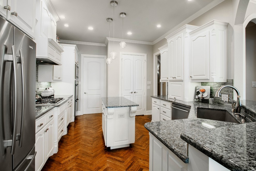 Exempel på ett mellanstort klassiskt grå grått kök, med en undermonterad diskho, luckor med upphöjd panel, vita skåp, bänkskiva i kvarts, stänkskydd med metallisk yta, stänkskydd i glaskakel, rostfria vitvaror, mellanmörkt trägolv, en köksö och brunt golv