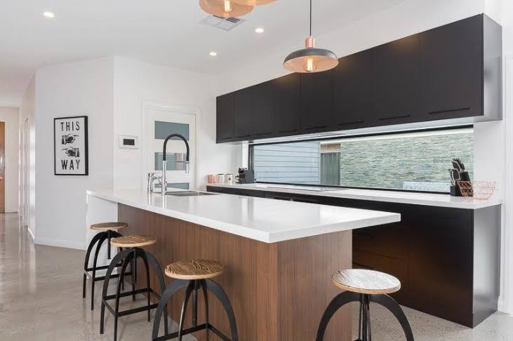 Foto di una piccola cucina contemporanea con lavello a doppia vasca, ante lisce, ante nere, top in granito, paraspruzzi con lastra di vetro e pavimento in cemento