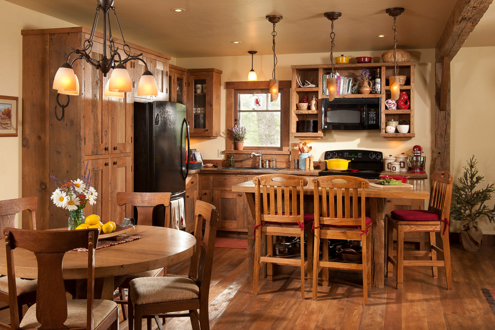 Small mountain style l-shaped medium tone wood floor and brown floor open concept kitchen photo in Other with a drop-in sink, shaker cabinets, distressed cabinets, wood countertops, brown backsplash, wood backsplash, black appliances and an island