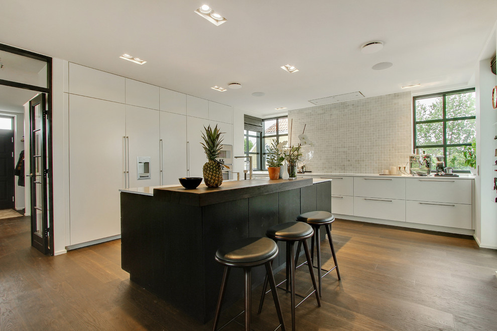 Large scandinavian u-shaped kitchen/diner in Wiltshire with a built-in sink, flat-panel cabinets, white cabinets, dark hardwood flooring and an island.