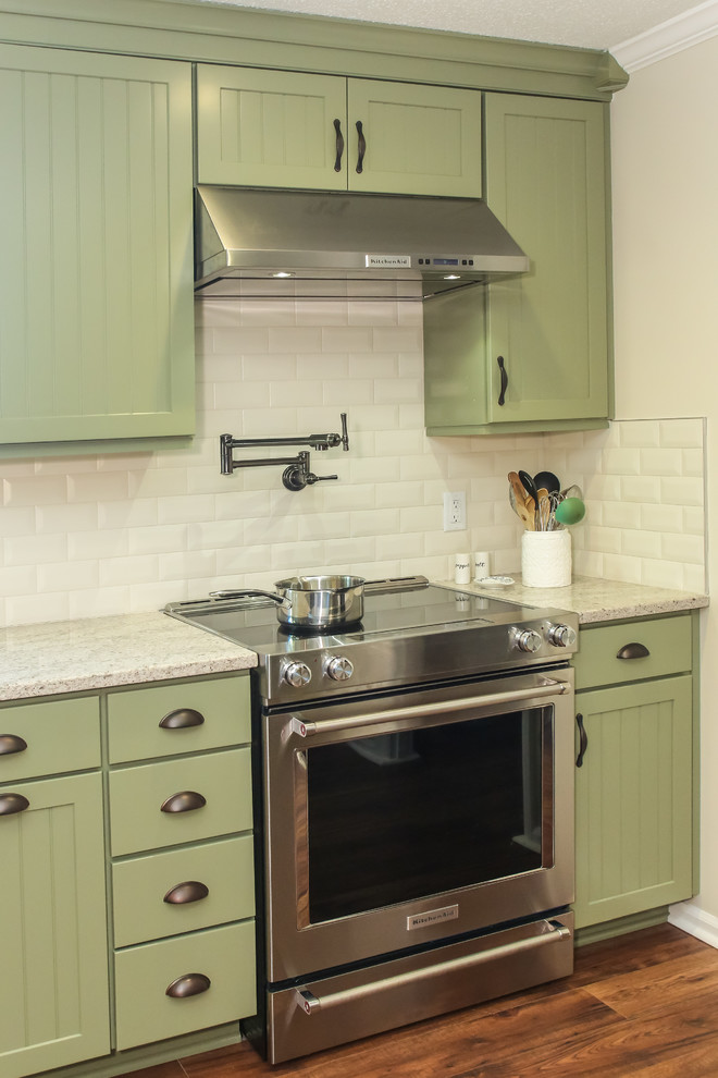アトランタにある広いカントリー風のおしゃれなキッチン (エプロンフロントシンク、インセット扉のキャビネット、緑のキャビネット、クオーツストーンカウンター、白いキッチンパネル、サブウェイタイルのキッチンパネル、シルバーの調理設備、無垢フローリング、茶色い床、マルチカラーのキッチンカウンター) の写真