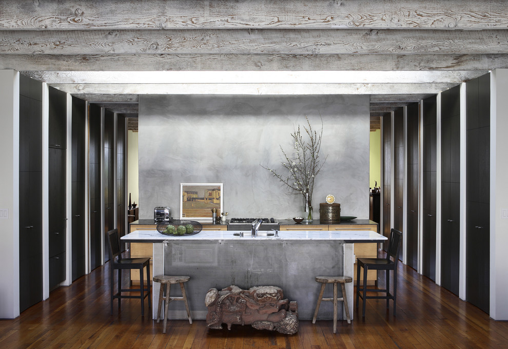 Cette photo montre une cuisine parallèle industrielle avec un placard à porte plane, des portes de placard noires, plan de travail en marbre et une crédence grise.