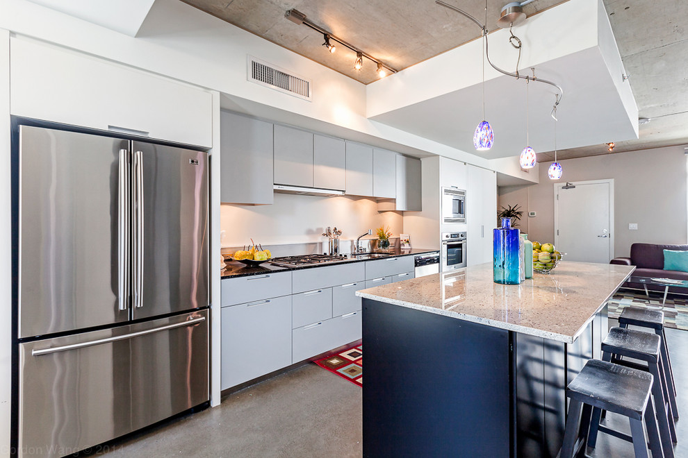 Example of a large urban galley concrete floor open concept kitchen design in Seattle with an undermount sink, flat-panel cabinets, gray cabinets, granite countertops, stainless steel appliances and an island