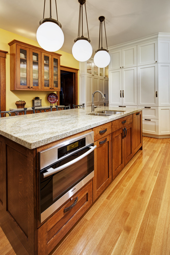 Imagen de cocina de estilo americano cerrada con armarios estilo shaker, puertas de armario de madera oscura, electrodomésticos de acero inoxidable y barras de cocina