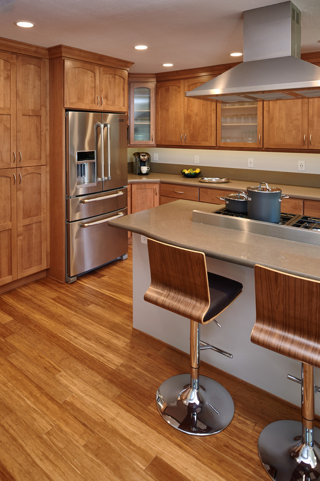 Стильный дизайн: угловая кухня в классическом стиле с обеденным столом, фасадами с утопленной филенкой, светлыми деревянными фасадами, техникой из нержавеющей стали, светлым паркетным полом и островом - последний тренд