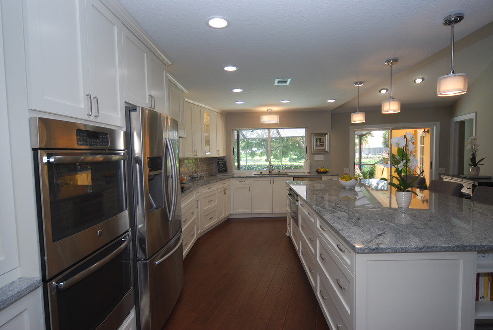 Klassische Wohnküche in L-Form mit Schrankfronten im Shaker-Stil, weißen Schränken, Küchenrückwand in Grau, Rückwand aus Metrofliesen, Küchengeräten aus Edelstahl und Kücheninsel in Tampa
