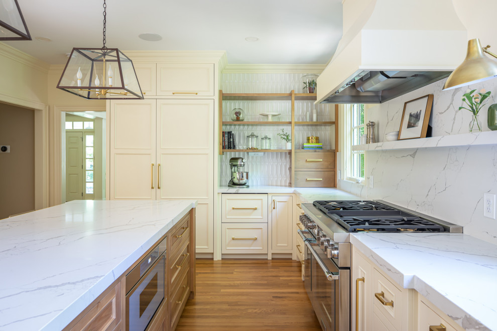 Inspiration for a large timeless u-shaped medium tone wood floor and brown floor enclosed kitchen remodel in Raleigh with an undermount sink, raised-panel cabinets, white cabinets, quartzite countertops, white backsplash, quartz backsplash, paneled appliances, an island and white countertops