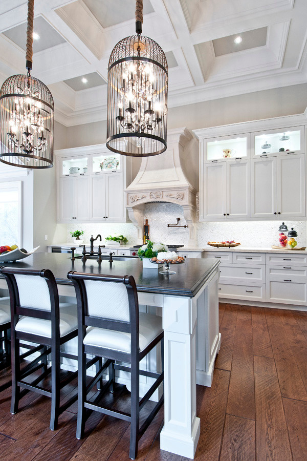 Photo of a traditional galley open plan kitchen in Toronto with a submerged sink, shaker cabinets, white cabinets, white splashback, integrated appliances, medium hardwood flooring, an island and brown floors.