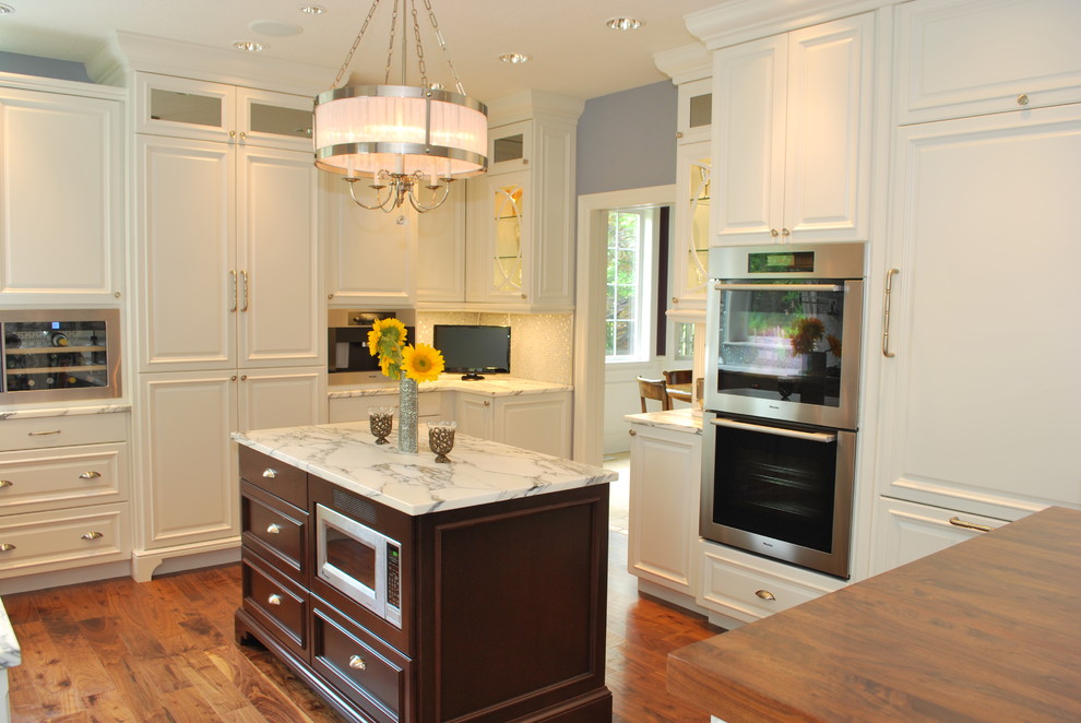 Foto de cocina actual con electrodomésticos con paneles y encimera de mármol