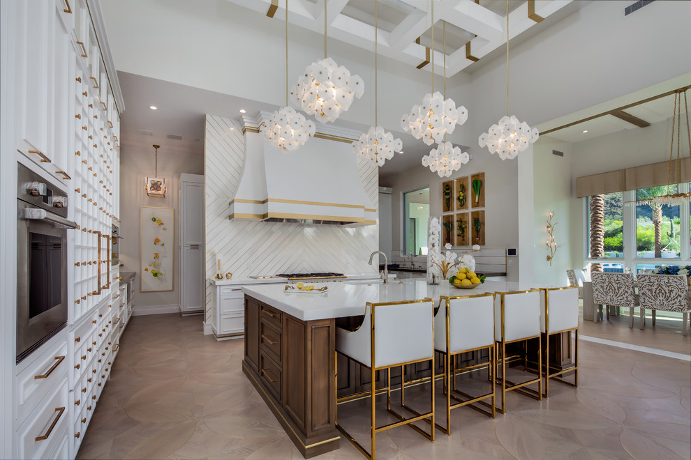 Large trendy u-shaped light wood floor and brown floor eat-in kitchen photo in Phoenix with a drop-in sink, white cabinets, marble countertops, white backsplash, marble backsplash, stainless steel appliances and an island