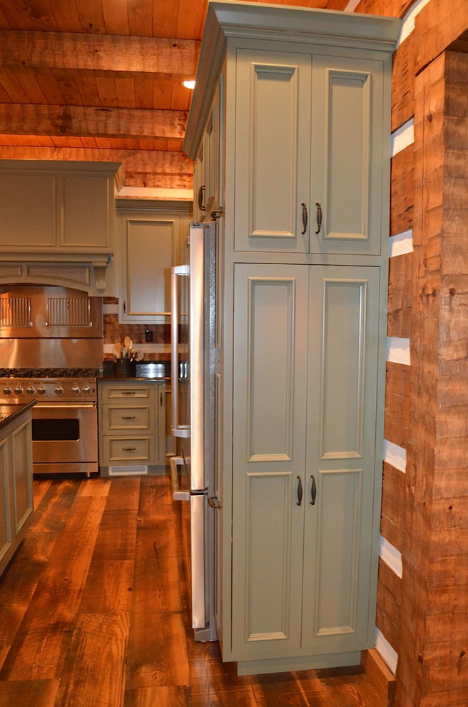 Foto på ett stort, avskilt rustikt u-kök, med en rustik diskho, gröna skåp, granitbänkskiva, rostfria vitvaror, en köksö, mellanmörkt trägolv, brunt stänkskydd, stänkskydd i trä och luckor med infälld panel