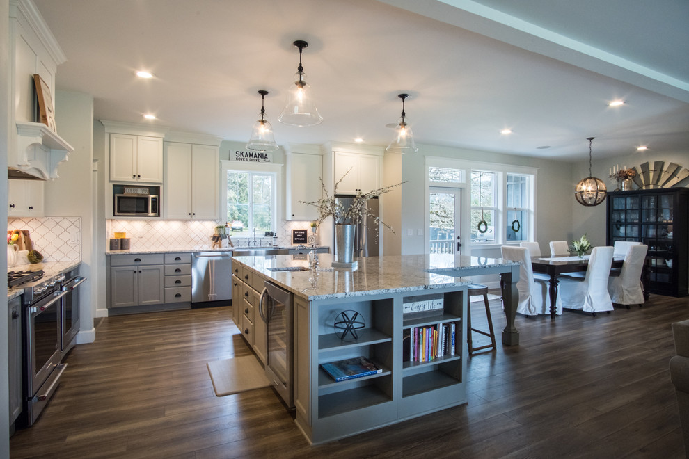 Exempel på ett stort klassiskt flerfärgad flerfärgat kök, med en rustik diskho, skåp i shakerstil, grå skåp, bänkskiva i kvarts, vitt stänkskydd, stänkskydd i keramik, rostfria vitvaror, laminatgolv, en köksö och brunt golv