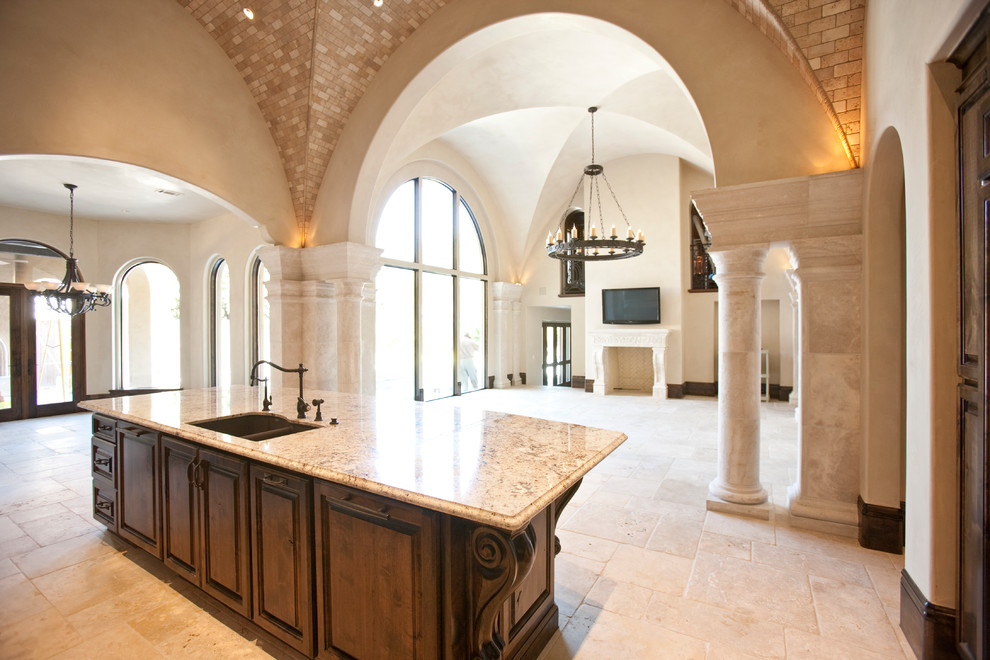 Foto de cocinas en L mediterránea, extra grande, abierta, con fregadero sobremueble, armarios con paneles con relieve, puertas de armario de madera en tonos medios, encimera de mármol, salpicadero beige, salpicadero de azulejos de piedra, electrodomésticos de acero inoxidable, suelo de travertino y una isla