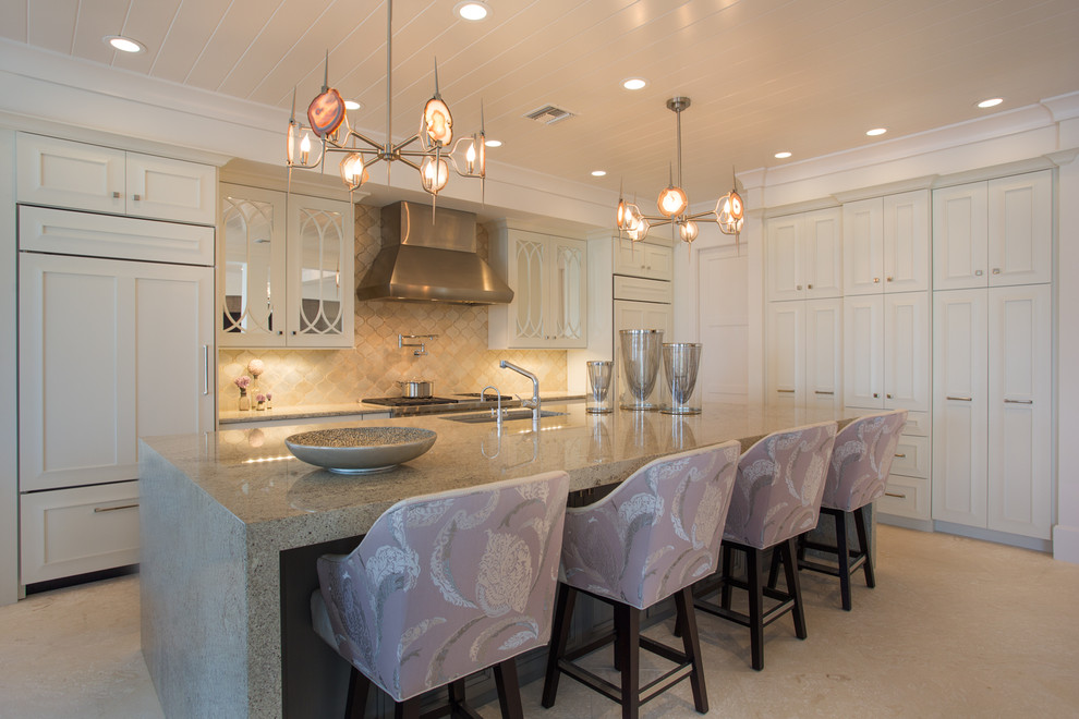 Mid-sized transitional l-shaped travertine floor kitchen photo in Miami with recessed-panel cabinets, white cabinets, granite countertops, beige backsplash, terra-cotta backsplash, paneled appliances and an island