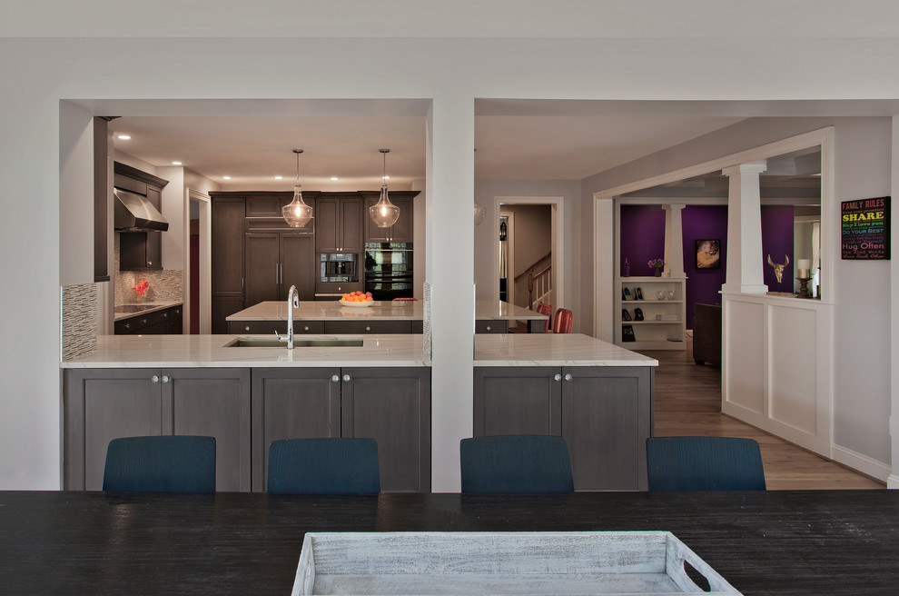 Example of a large minimalist light wood floor eat-in kitchen design in DC Metro with an undermount sink, recessed-panel cabinets, gray cabinets, quartzite countertops, gray backsplash, stone tile backsplash, stainless steel appliances and an island