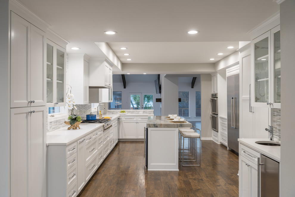 Eat-in kitchen - large transitional l-shaped medium tone wood floor and brown floor eat-in kitchen idea in Dallas with a single-bowl sink, shaker cabinets, white cabinets, stainless steel appliances, an island, quartz countertops, gray backsplash and mosaic tile backsplash
