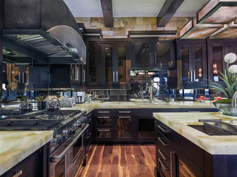 Example of a large trendy u-shaped medium tone wood floor enclosed kitchen design in Denver with an undermount sink, glass-front cabinets, black cabinets, metallic backsplash, mirror backsplash, stainless steel appliances and an island