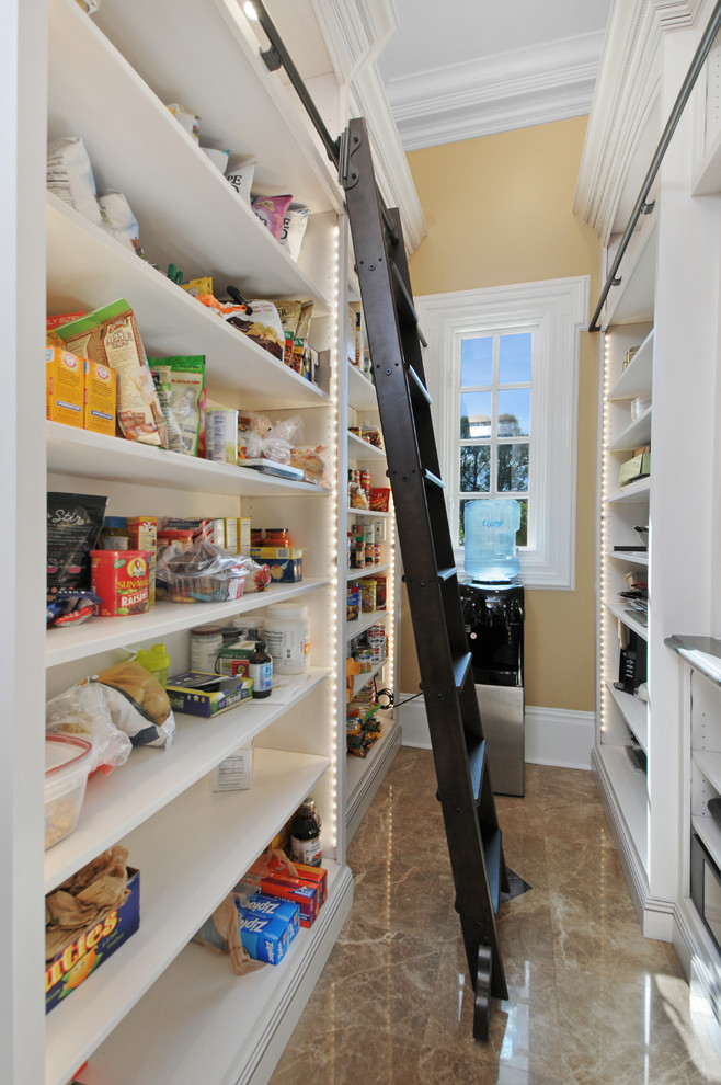 Photo of an expansive traditional u-shaped kitchen pantry in Tampa with a submerged sink, raised-panel cabinets, white cabinets, engineered stone countertops, white splashback, metro tiled splashback, stainless steel appliances, marble flooring, an island and beige floors.