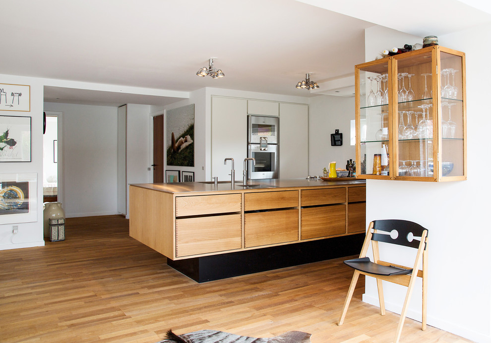 Immagine di un cucina con isola centrale minimal con lavello a doppia vasca, ante di vetro, ante in legno scuro, top in legno, pavimento in legno massello medio e pavimento marrone