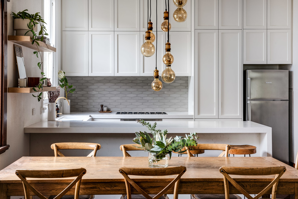 Inspiration for a classic u-shaped kitchen/diner in Perth with shaker cabinets, white cabinets, grey splashback, stainless steel appliances, a breakfast bar and white worktops.